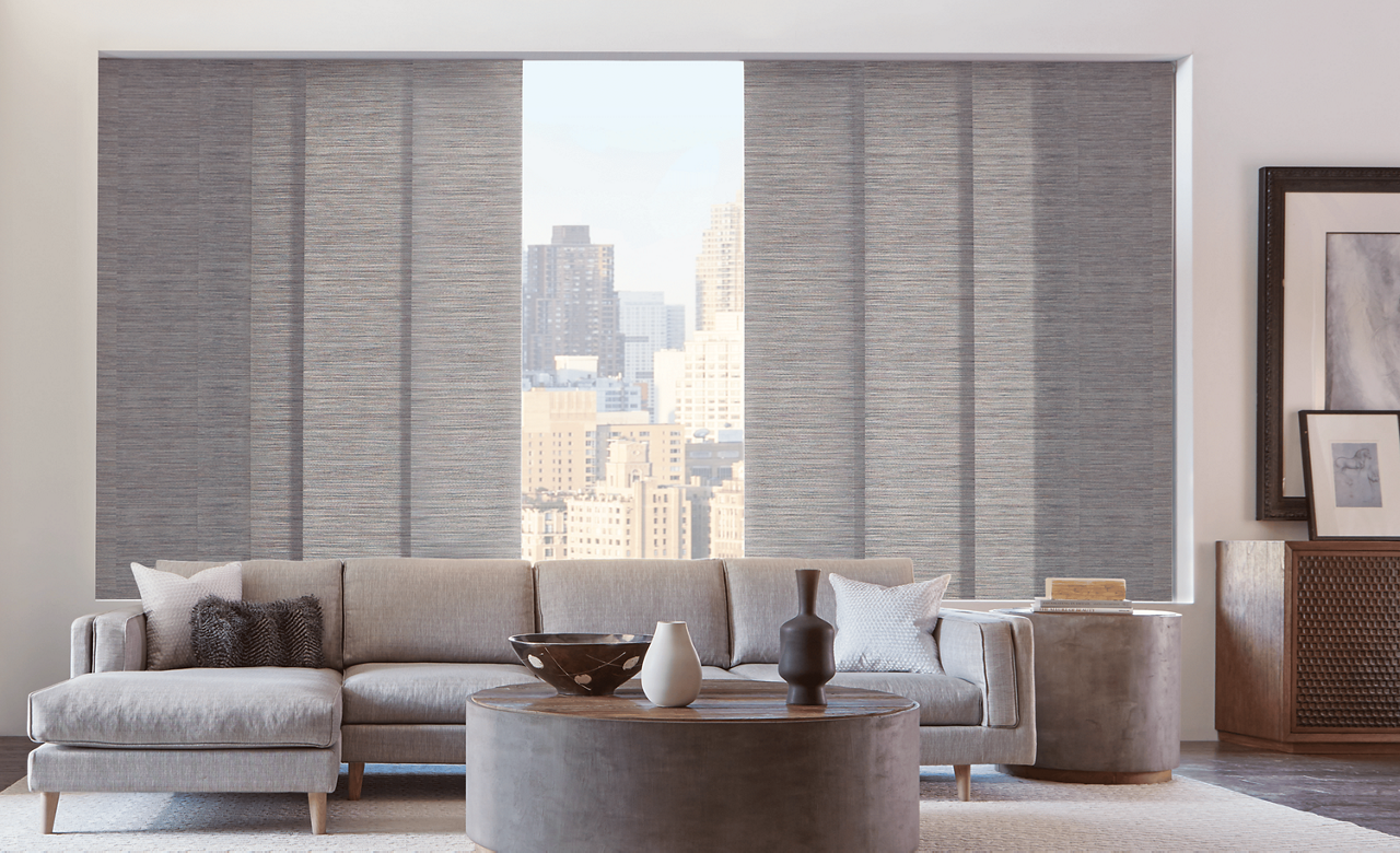 Living room featuring large windows with Hunter Douglas Skyline® Panel Track Blinds.